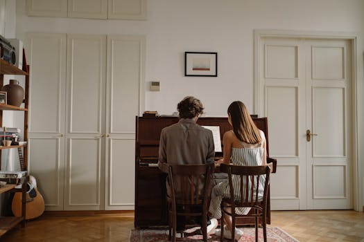 A couple sitting together and playing piano in a cozy home interior setting.
